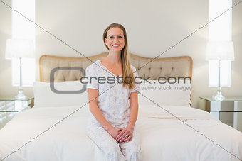 Natural cheerful woman sitting on bed
