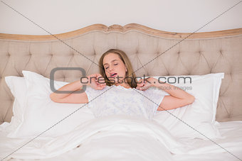 Natural tired woman yawning and resting in bed