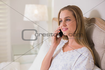 Natural calm woman sitting in bed phoning