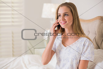 Natural happy woman sitting in bed phoning