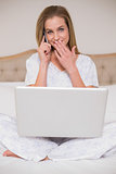 Natural surprised woman using laptop and phoning