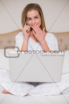 Natural surprised woman using laptop and phoning
