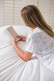 Natural woman lying on bed reading