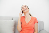 Laughing casual woman phoning with her smartphone sitting on couch
