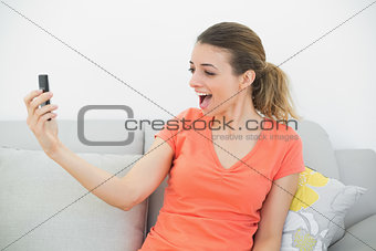 Surprised casual woman looking at her smartphone