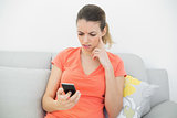 Troubled brunette woman using her smartphone sitting on couch