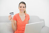 Content smiling woman showing her credit card while holding her notebook
