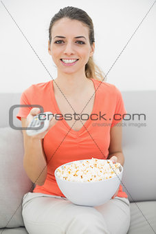 Peaceful brunette woman watching television sitting on couch