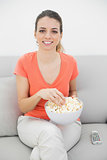 Attractive smiling woman eating popcorn while watching television