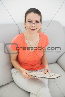Young brunette woman sitting on couch holding a magazine
