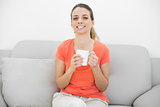 Cheerful beautiful woman holding a cup sitting on couch