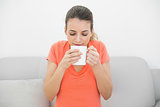 Lovely calm woman smelling a cup sitting on couch