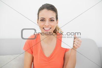 Content brunette woman showing a cup smiling at camera