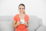 Happy brunette woman holding a cup smiling at camera