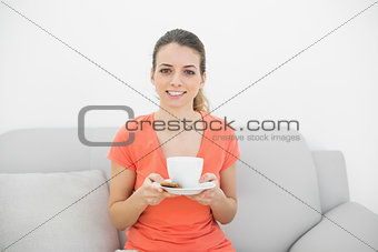 Happy brunette woman holding a cup smiling at camera