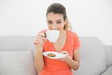 Cute brunette woman smelling a cup sitting on couch