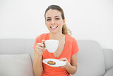Attractive brunette woman holding a cup smiling cheerfully at camera