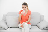 Attractive casual woman drinking a glass of water looking at camera