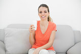 Cheerful brunette woman holding a glass of milk smiling happily at camera