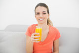 Beautiful calm woman smiling at camera holding a glass of orange juice