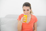 Gorgeous calm woman drinking a glass of orange juice looking at camera