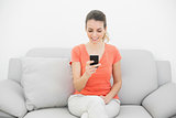 Happy gorgeous woman using her smartphone cheerfully