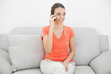 Beautiful cute woman phoning with smartphone sitting on couch