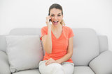 Cheering casual woman phoning sitting on couch