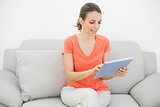 Happy young woman working with her  tablet sitting on couch