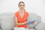 Amused casual woman using her tablet smiling cheerfully at camera
