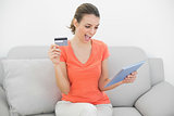 Attractive woman showing her credit card holding her tablet
