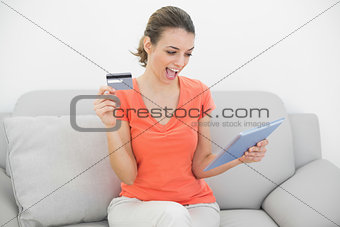 Attractive woman showing her credit card holding her tablet
