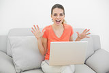 Portrait of cute cheering woman using her notebook sitting on couch