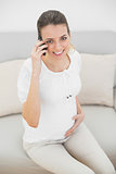 Lovely pregnant woman phoning with smartphone holding her belly