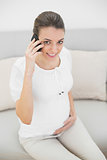 Peaceful pregnant woman phoning holding her belly proudly