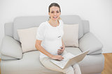 Content pregnant woman using her laptop smiling at camera