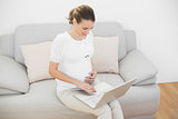 Peaceful young pregnant woman working with her laptop sitting on couch