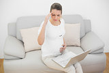 Pregnant woman having headache touching her belly sitting on couch