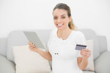 Attractive pregnant woman showing cheerfully her credit card and tablet