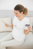 Lovely pregnant woman home shopping with her tablet