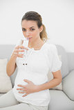 Beautiful pregnant woman touching her belly drinking a glass of water