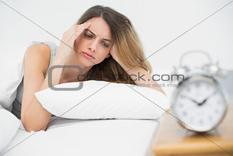 Suffering young woman having headache lying on her bed