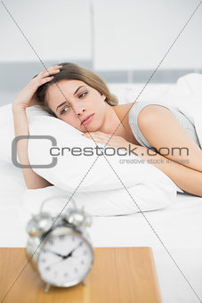 Gorgeous thinking woman lying on her bed under the cover