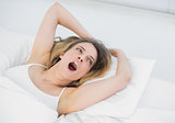 Pretty brunette woman yawning lying on her bed