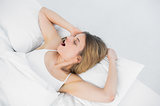 Lovely young woman yawning while lying on her bed