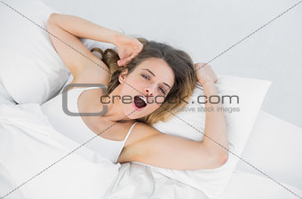 Young yawning woman lying on her bed in bedroom