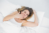 Gorgeous tired woman yawning lying on her bed