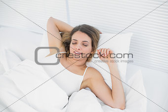 Content brunette woman relaxing lying on her bed