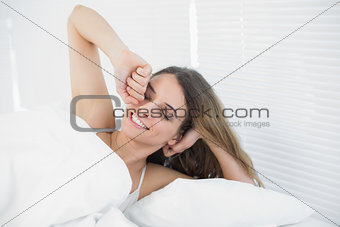 Smiling young woman waking up lying in her bed