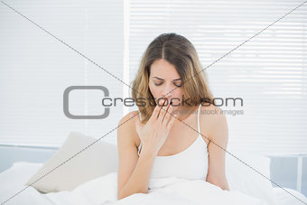 Tired woman sitting on her bed yawning